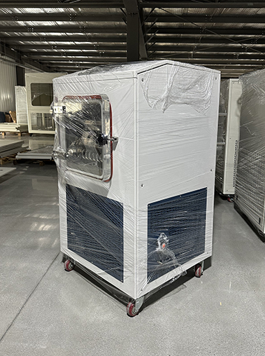 Left side angled view of a plastic-wrapped white vacuum freeze dryer lyophilizer unit on a factory floor.
